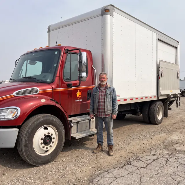 Truck driver standing with a Shipluxe LLC truck