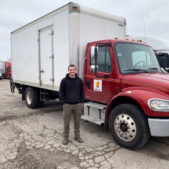 Truck driver standing with a Shipluxe LLC truck