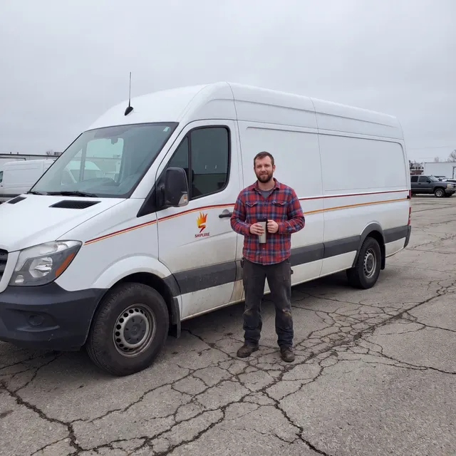 Truck driver standing with a Shipluxe LLC truck