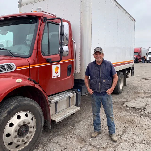 Truck driver standing with a Shipluxe LLC truck