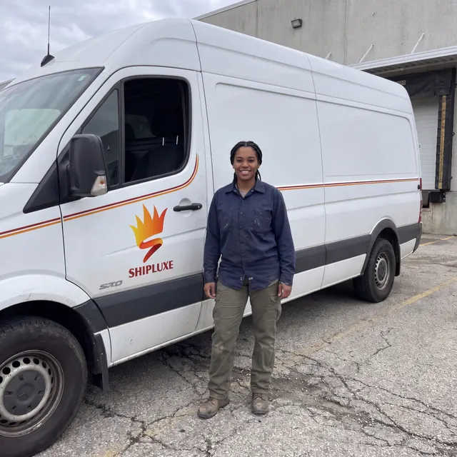 Truck driver standing with a Shipluxe LLC truck